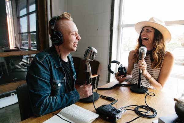 Branden Harvey and Ruthie Lindsey record a podcast together while laughing and smiling