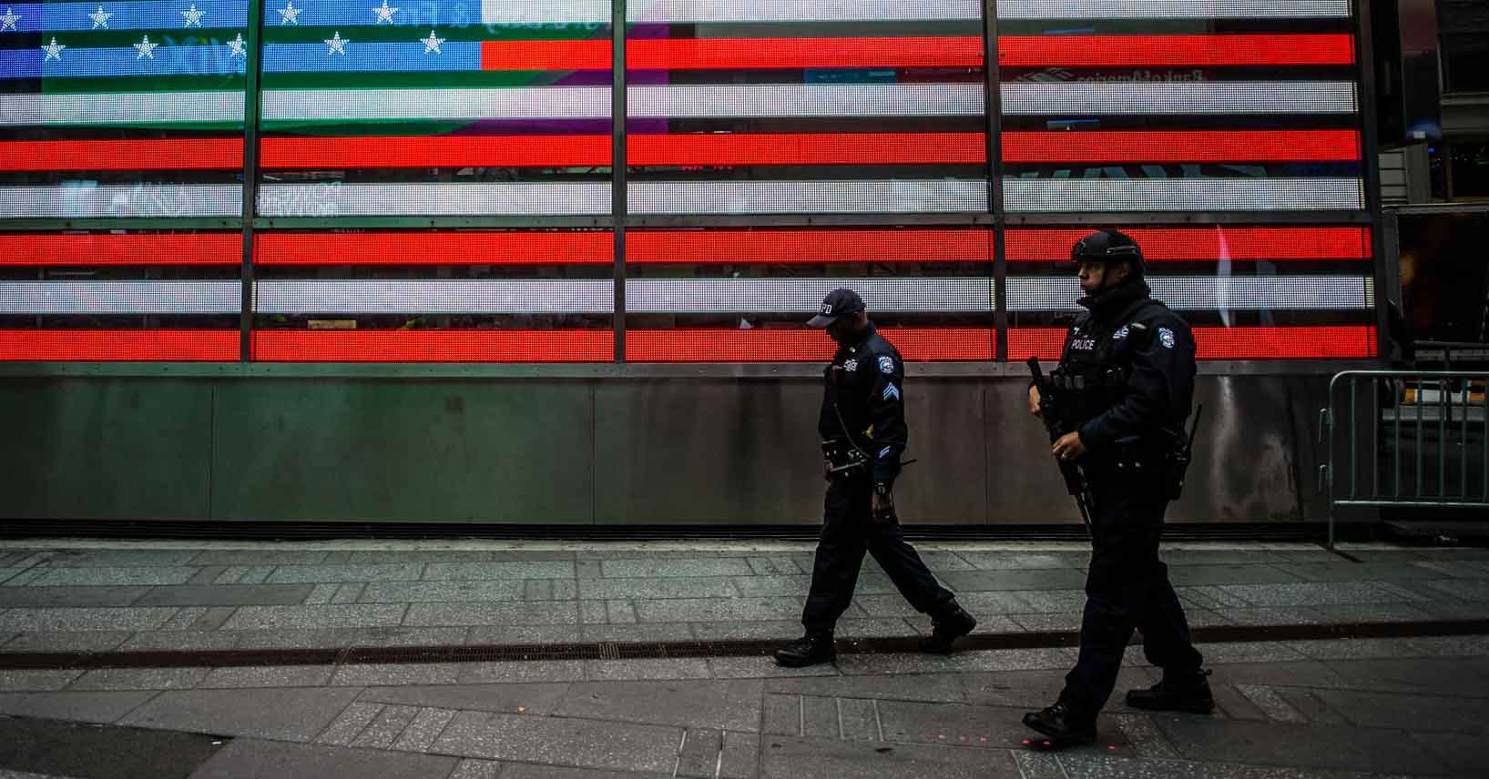 Police officers walking past an American flag