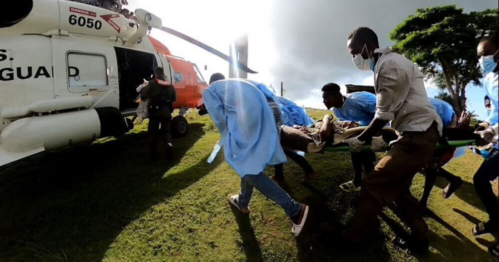 Emergency volunteers rushing a patient to a helicopter in Haiti