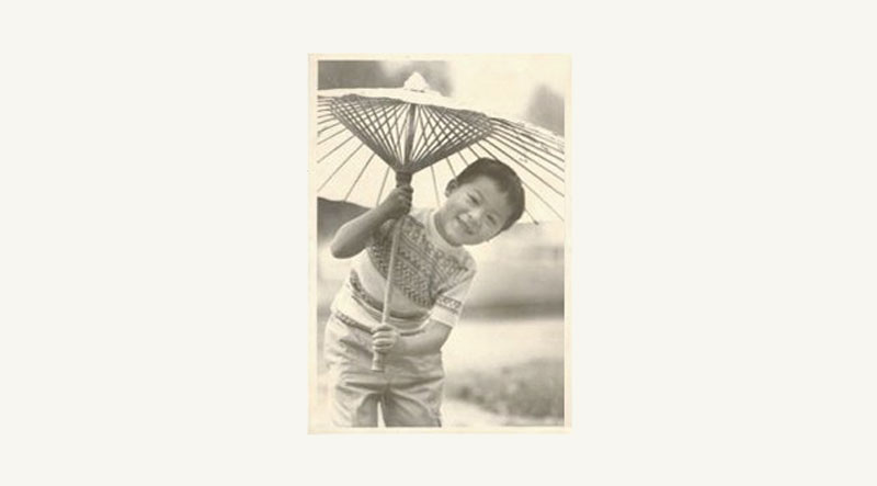 Jason Wang as a young child posing under a decorative umbrella in a vintage photo