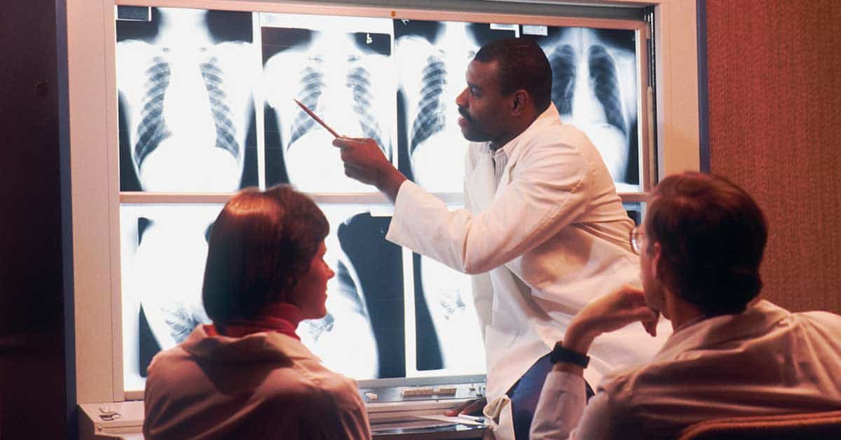 A Radiologist Examines Chest X-rays in front of two colleagues
