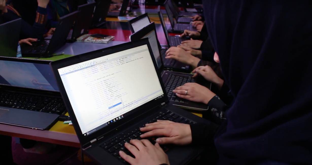 Girls learn how to code on laptops in Afghanistan.
