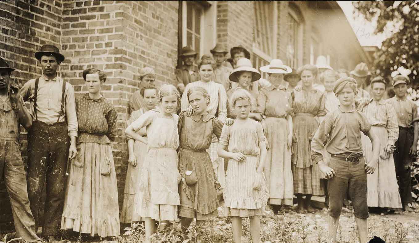 A group of children and adults who are cotton mill laborers in the United States