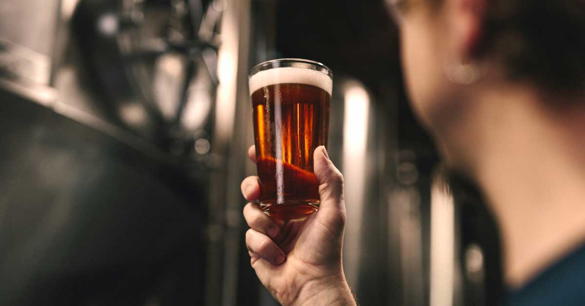 A sustainably produced pint of beer, being held up by a brew master in a micro brewery.