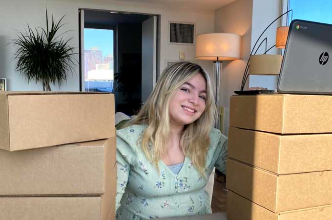 Teen girl poses with boxes of laptop to be donated