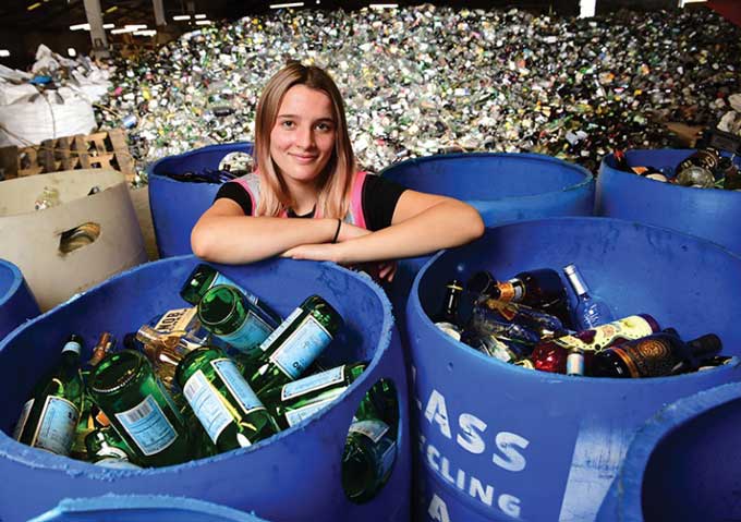 Franziska Trautmann poses with a warehouse full of glass bottles for recycling