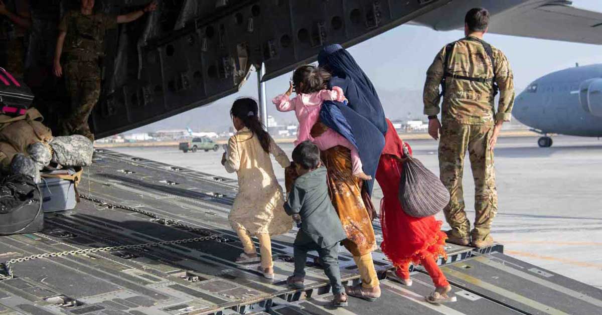 Afghan refugee family boarding a plane in Afghanistan, surrounded by U.S. military
