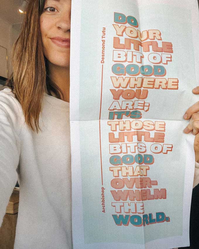 Girl holding poster of Desmond Tutu quotes about hope and injustice: “Do your little bit of good where you are; it is those little bits of good put together that overwhelm the world.”