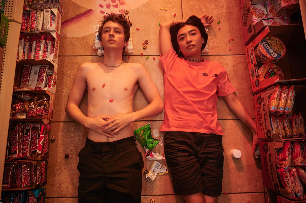 A still from the film 'Three Months', picturing Troye Sivan, who plays Caleb, and Brianne Tju, who plays Dara, lying on the floor of a grocery store.