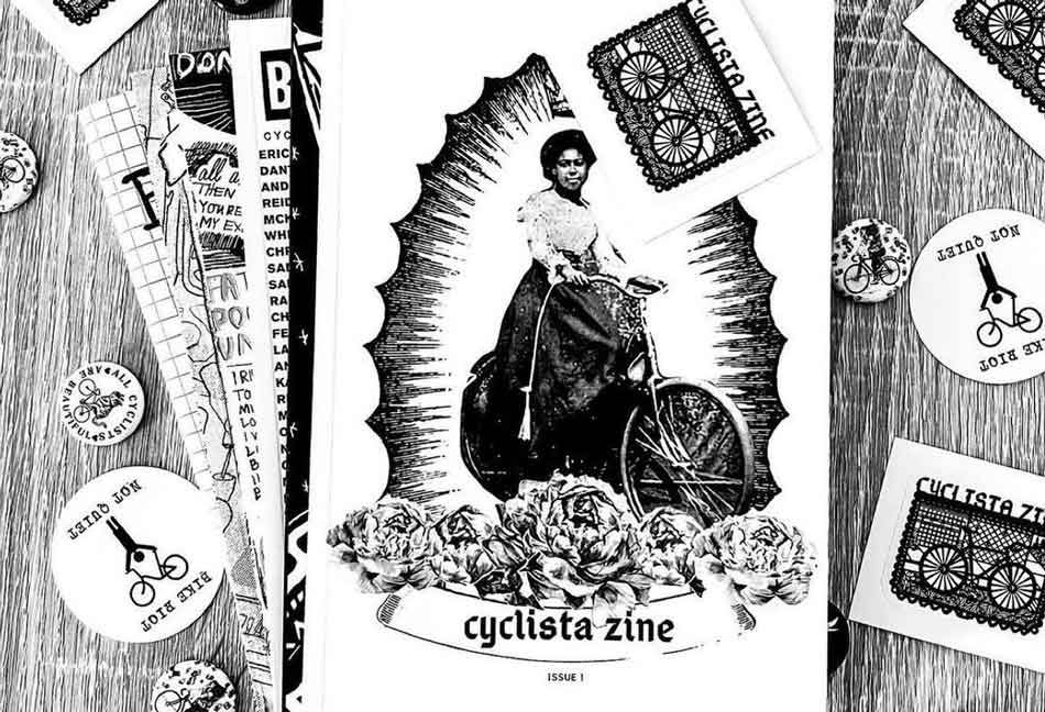 A copy of Cyclista Zine sits on a table surrounded by buttons and stickers.