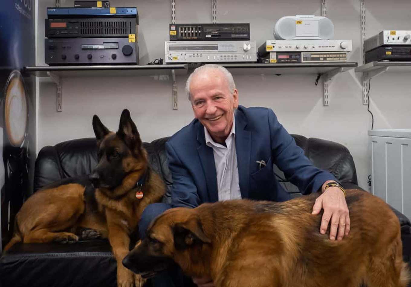 Sepp Eisenriegler poses smiling to the camera with his two dogs
