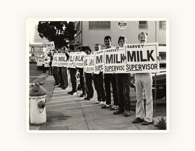 A group of people holding "Harvey Milk Supervisor" signs on Market Street