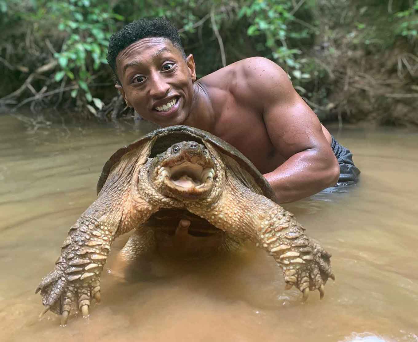 Christian Cave holding a Common Snapping Turtle in the water