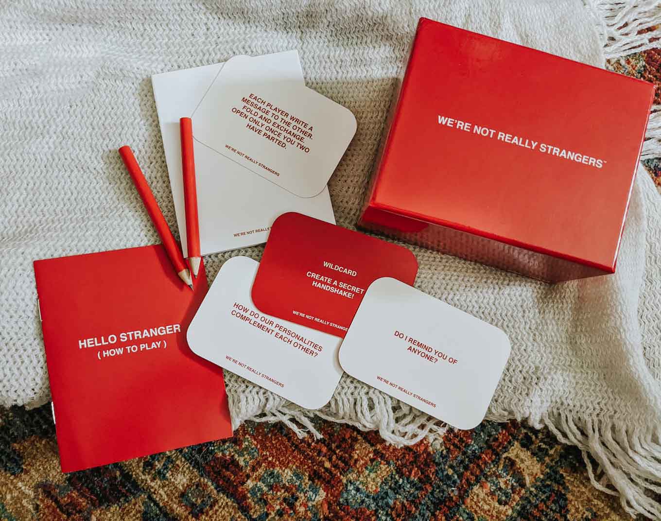 Red and white card deck that says "We're Not Really Strangers" with a red pencil and paper