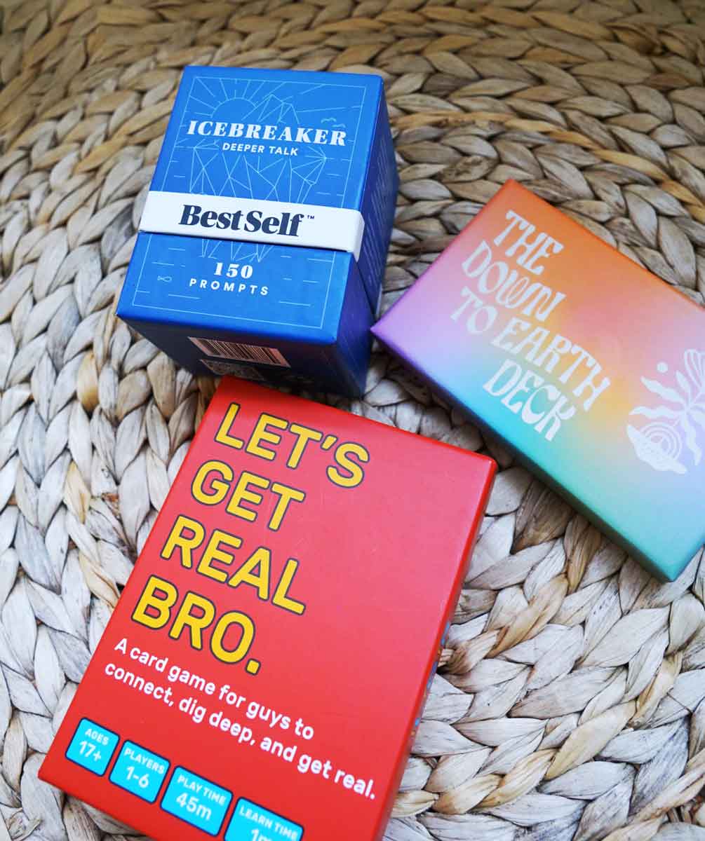 Three decks of conversation cards sitting next to each other:  BestSelf's Icebreaker Deeper Talk Deck, LOAM's The Down To Earth Deck, and Let's Get Real Bro