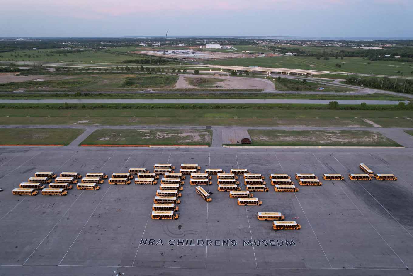 Dozens of school buses parked in the shape of a gun, with the words NRA Children's Museum