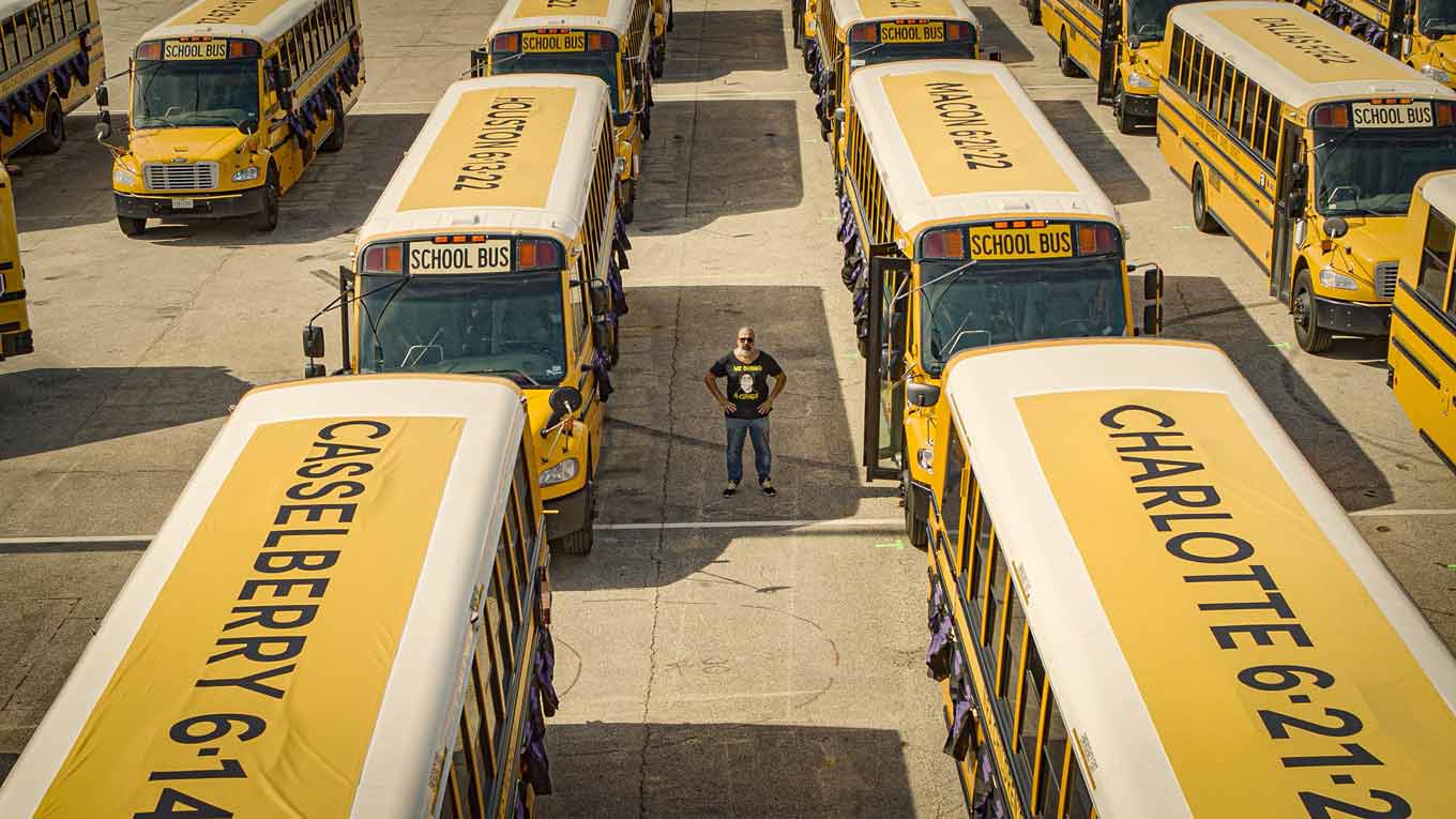 Manuel Oliver, standing among yellow school buses