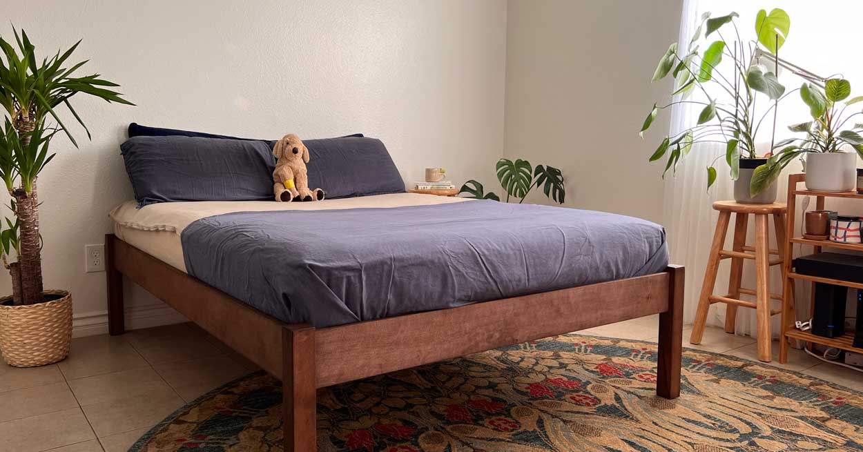 An eco-friendly bed frame made of wood, styled in a bedroom with plants