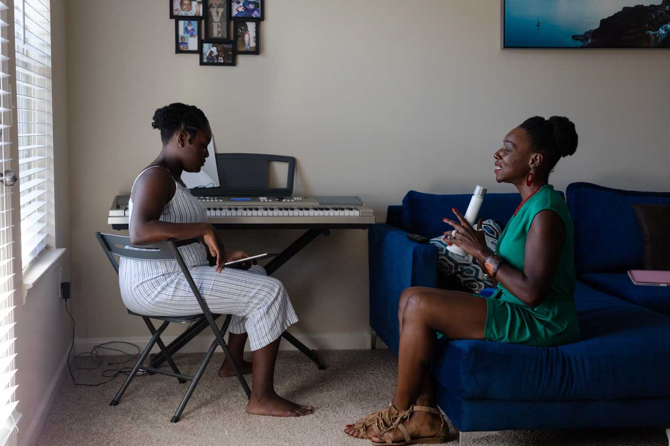Terri talking to her daughter while both of them are seated, Terri in a blue couch and Amari in a chair in front of her piano