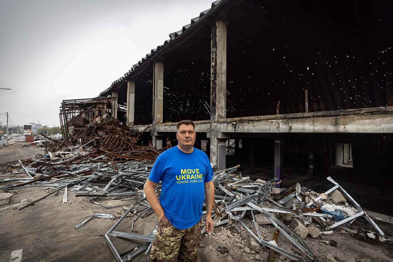 A MoveUkraine team member stands in front of a destroyed building
