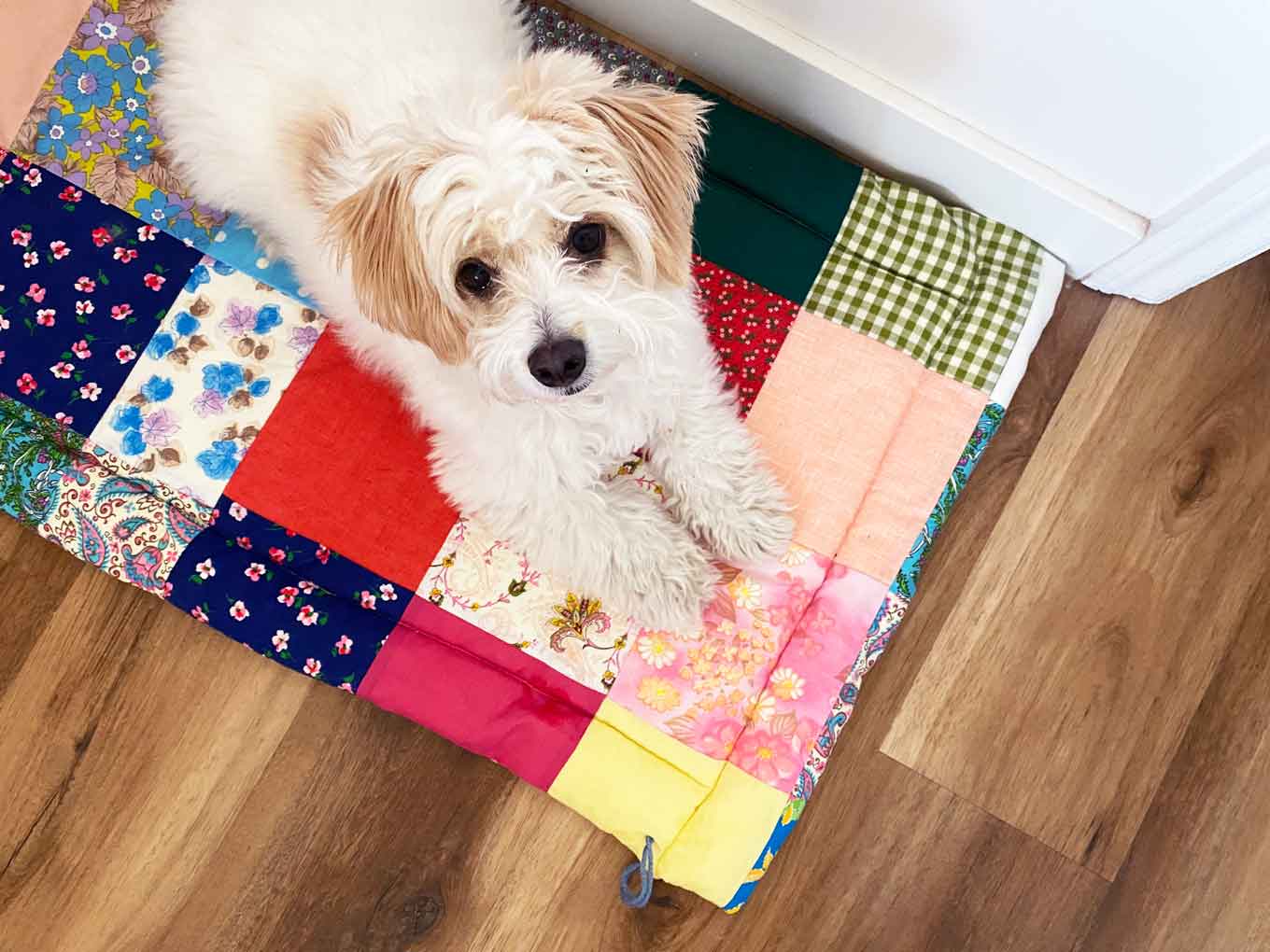 An eco-friendly dog mat made of patch-worked fabric, with a dog laying on it