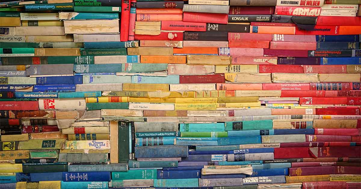 A pile of books organized in a rainbow color coded pattern