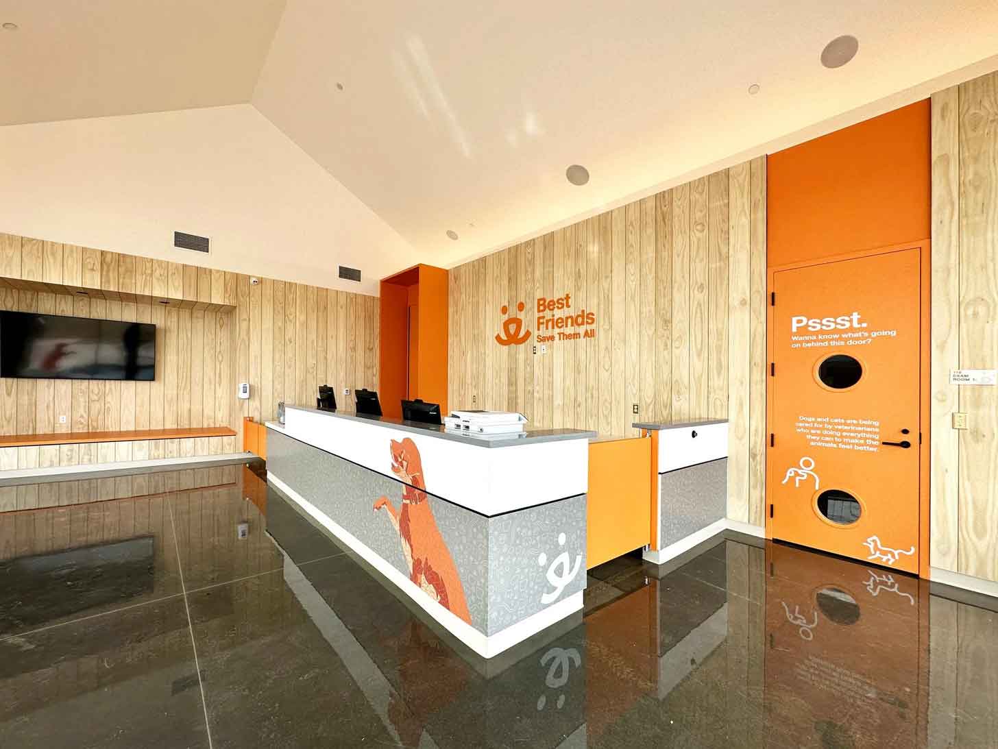 The front desk of Best Friends Pet Resource Center, featuring orange accents and a small window in the door for dogs to see out