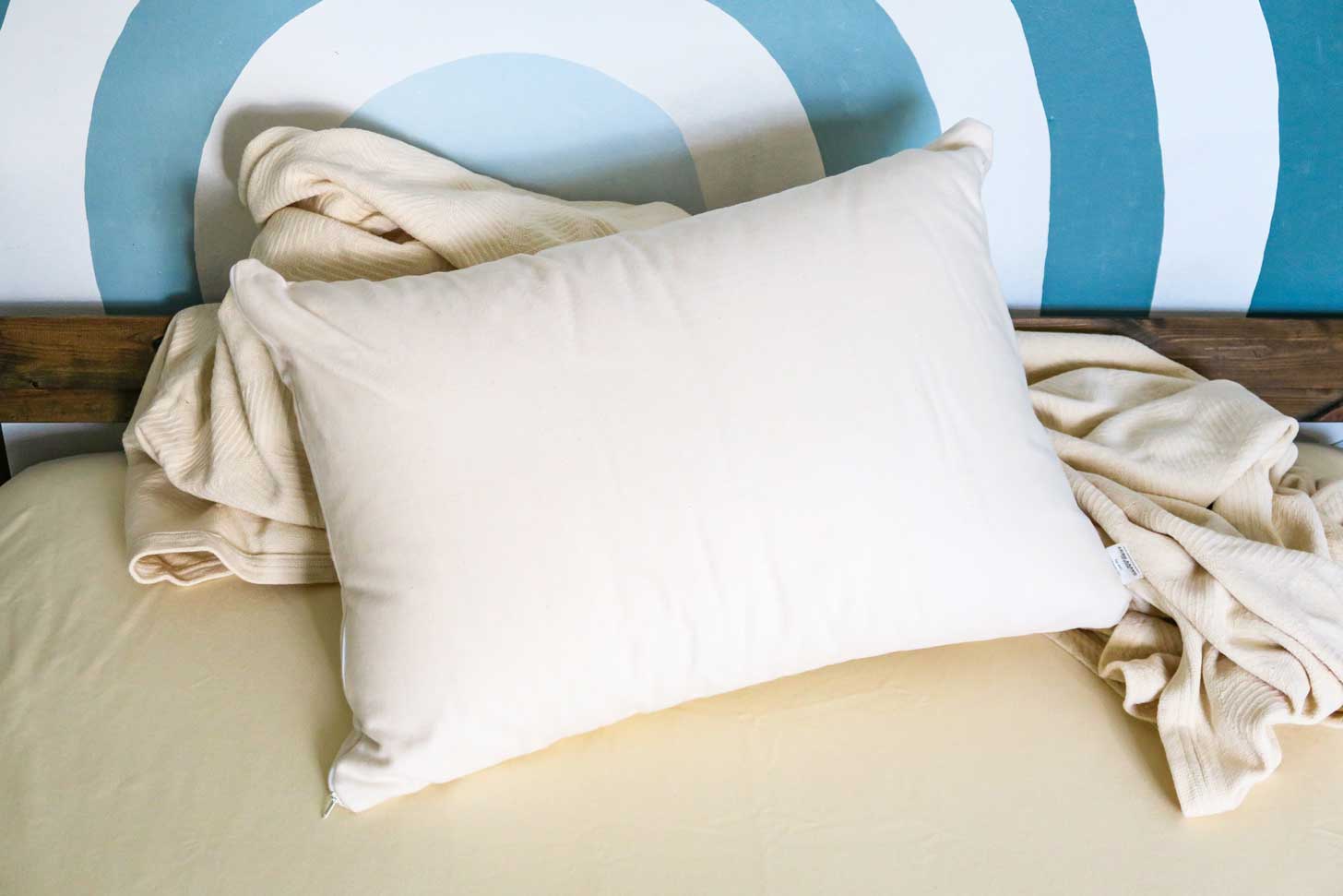 A Kappok pillow on a bed next to blankets