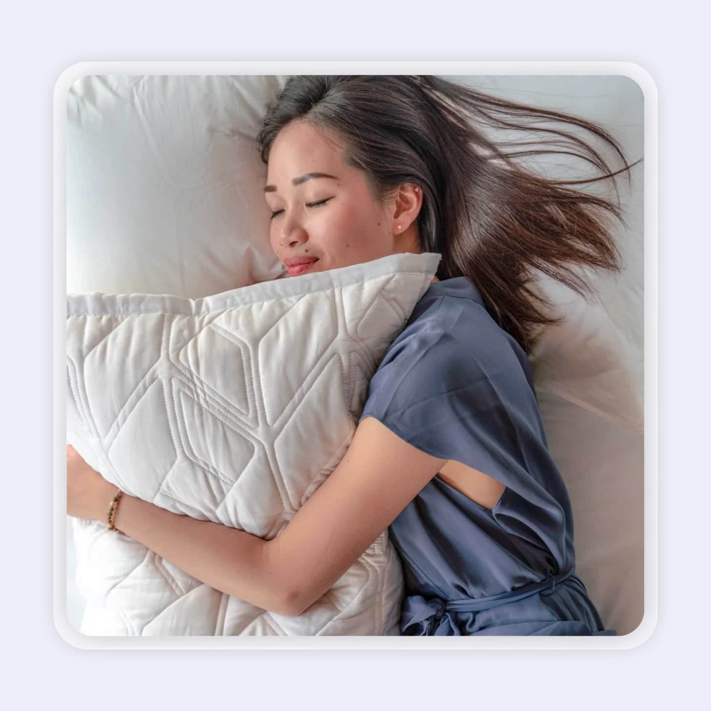 A woman hugs a pillow with a modern design in bed