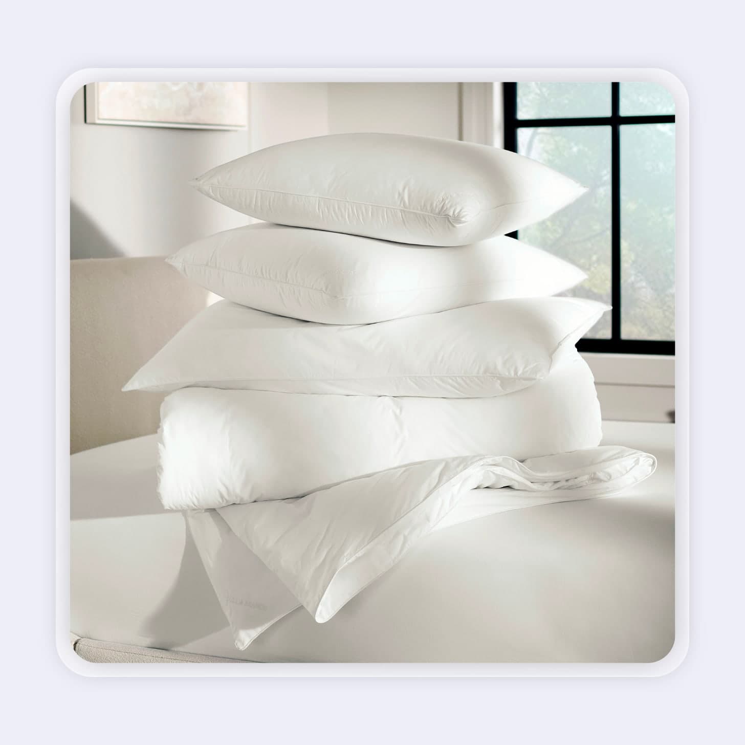 Three pillows stacked on top of bedding