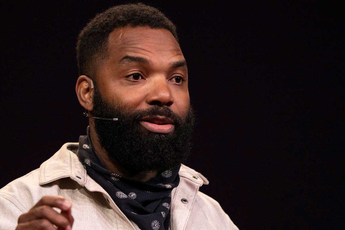 A Black man with a beard speaks on stage.