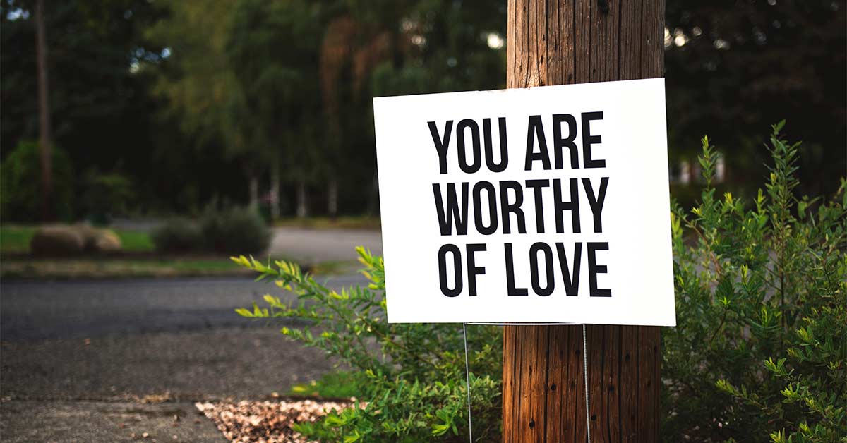 A sign on a tree that says "You are worthy of love"
