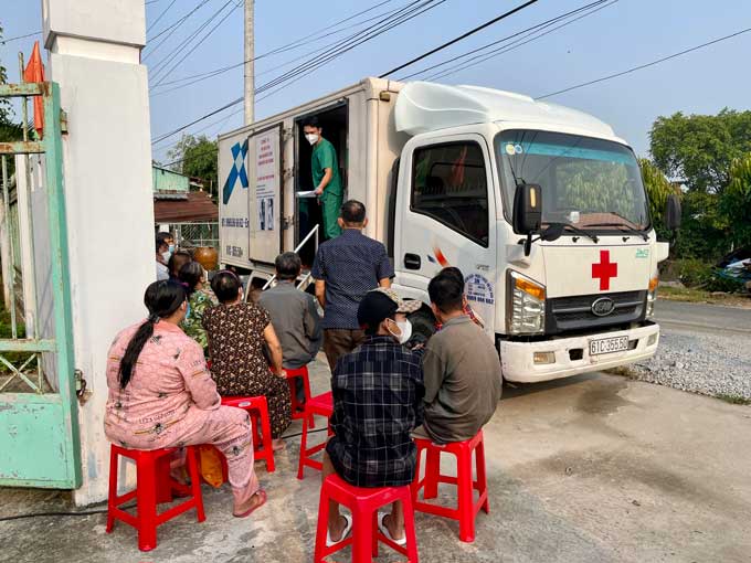 A group of people waits outside of a mobile medical clinic in Vietnam