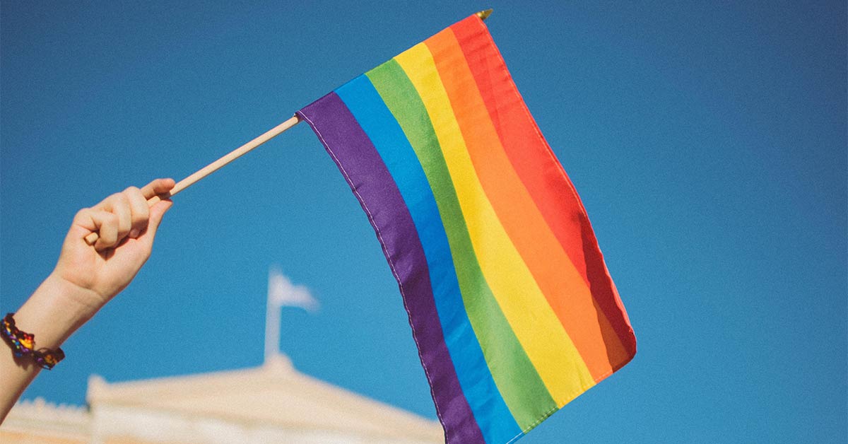 A person waving a rainbow LGBTQ+ Pride flag