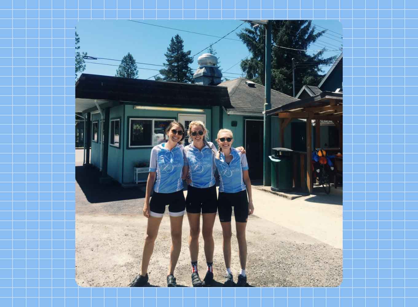 Three white women stand side-by-side in matching blue bike jerseys and black bike shorts, smiling.