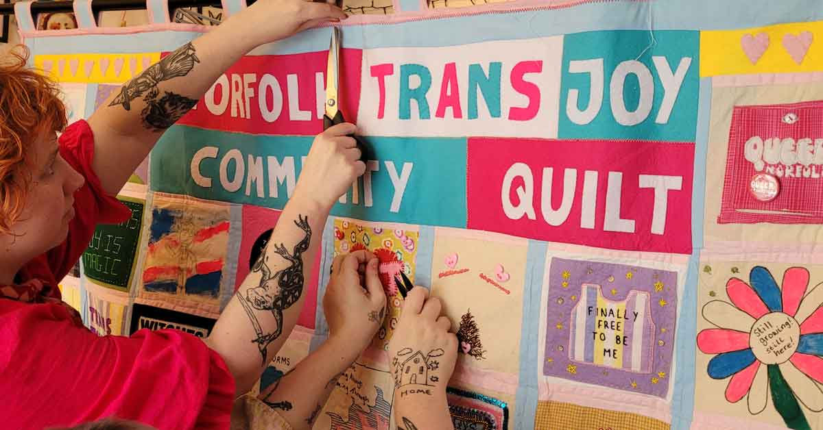 Hands work together to finalize patches on the Norfolk Trans Joy Community Quilt