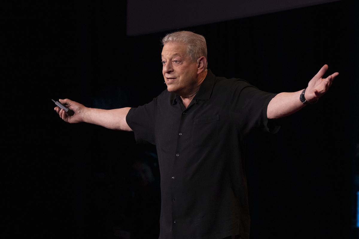 Al Gore stands on stage, extending his arms