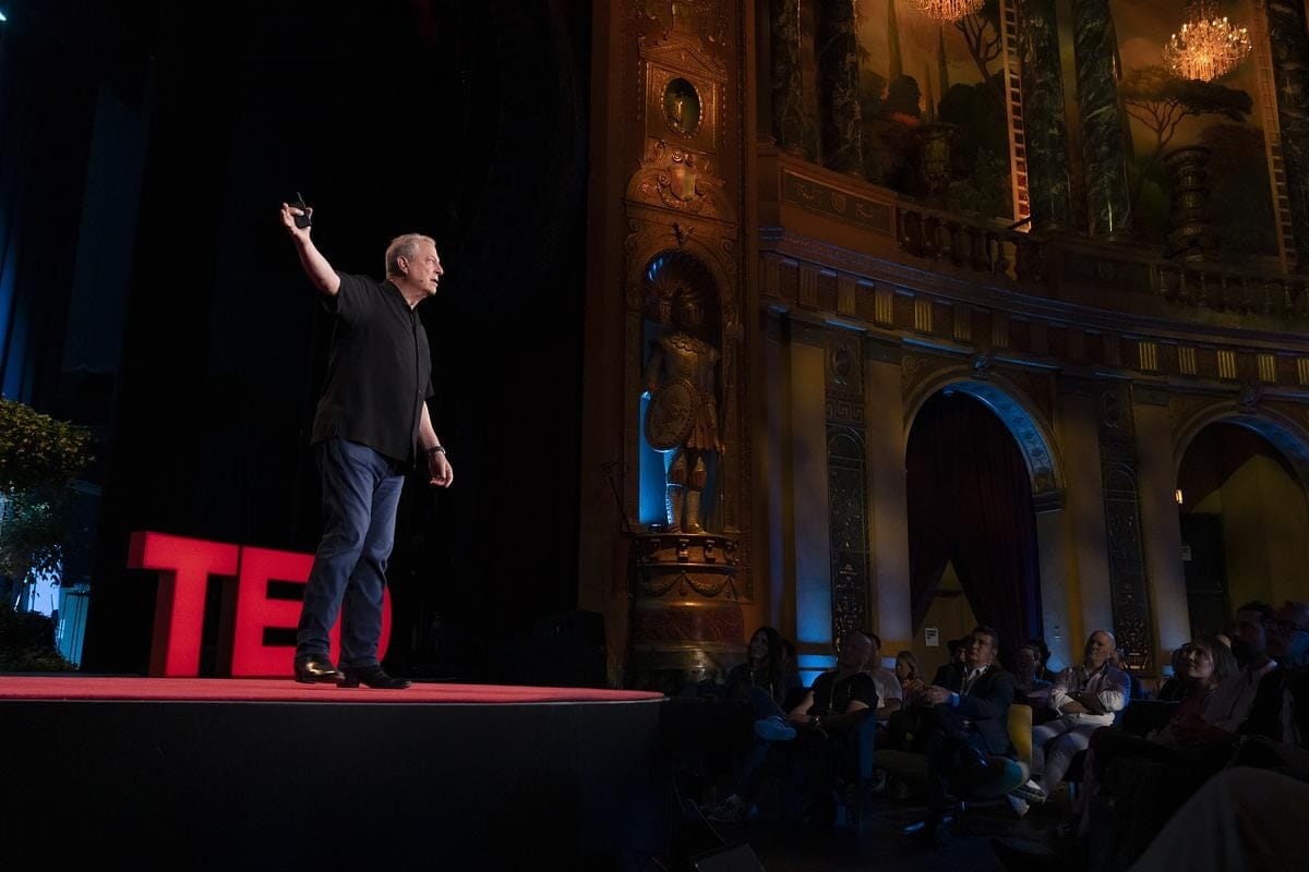 Al Gore stands on stage, one arm raised