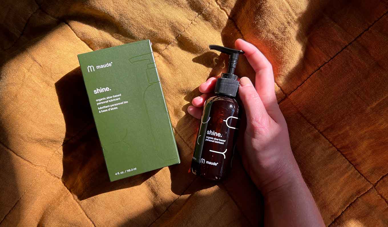 A hand holds a bottle of shine lubricant next to its green box.