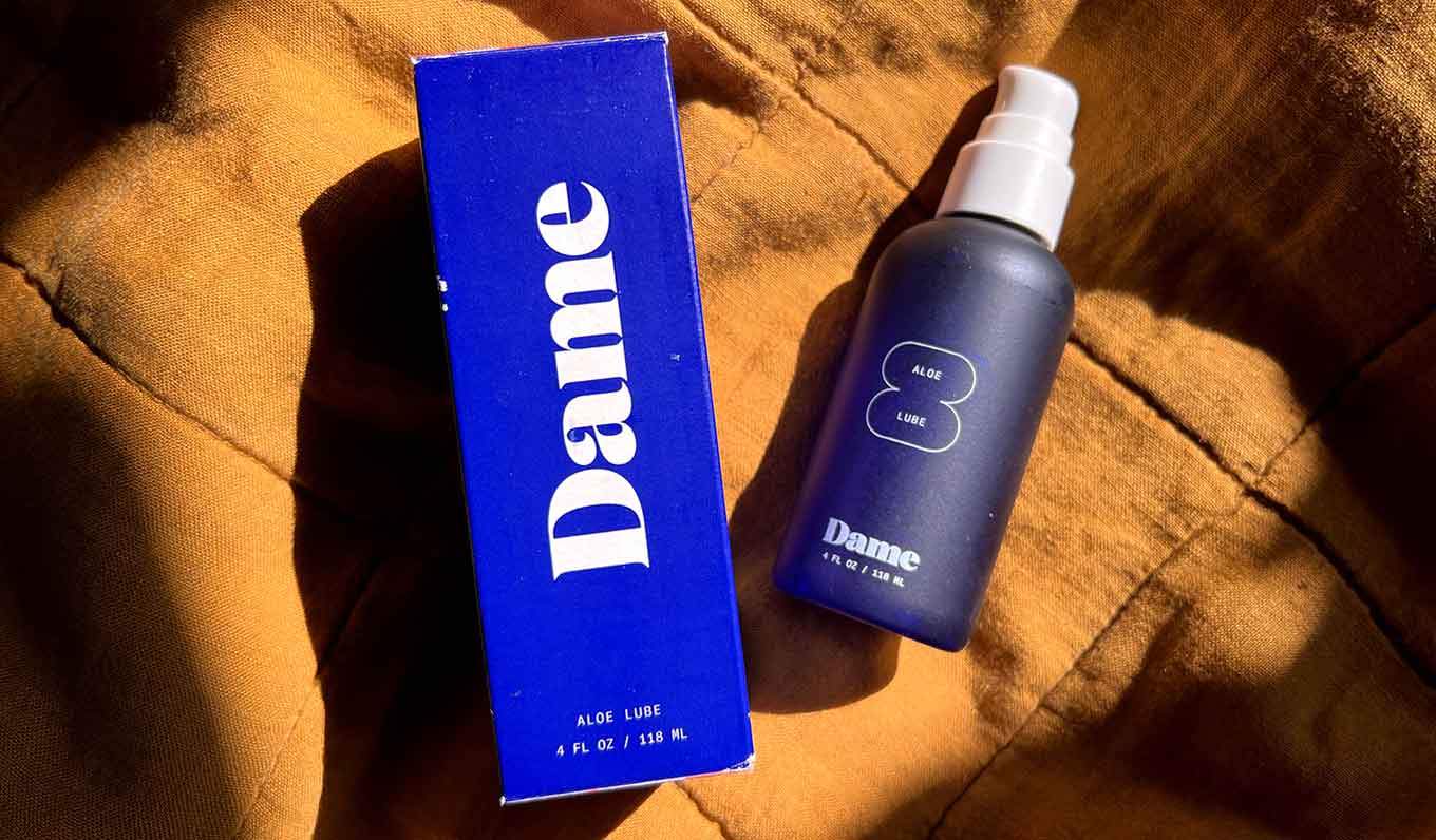 A royal blue box sits next to a blue bottle of Dame's aloe lube