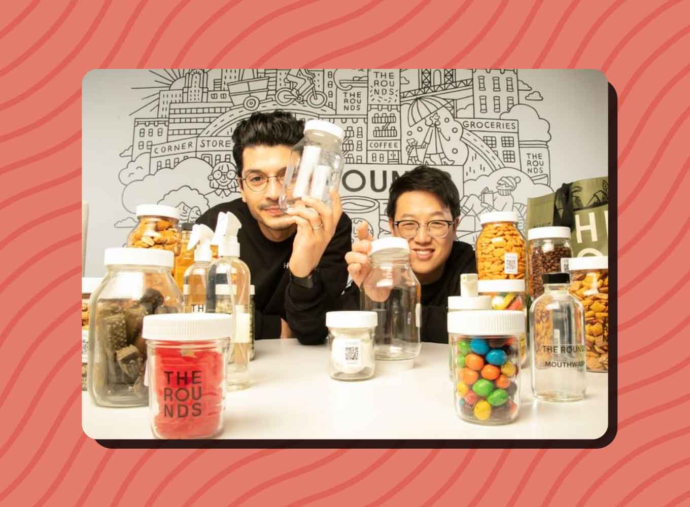 Alex Torrey and Byungwoo Ko smile behind a variety of jars containing different snack foods
