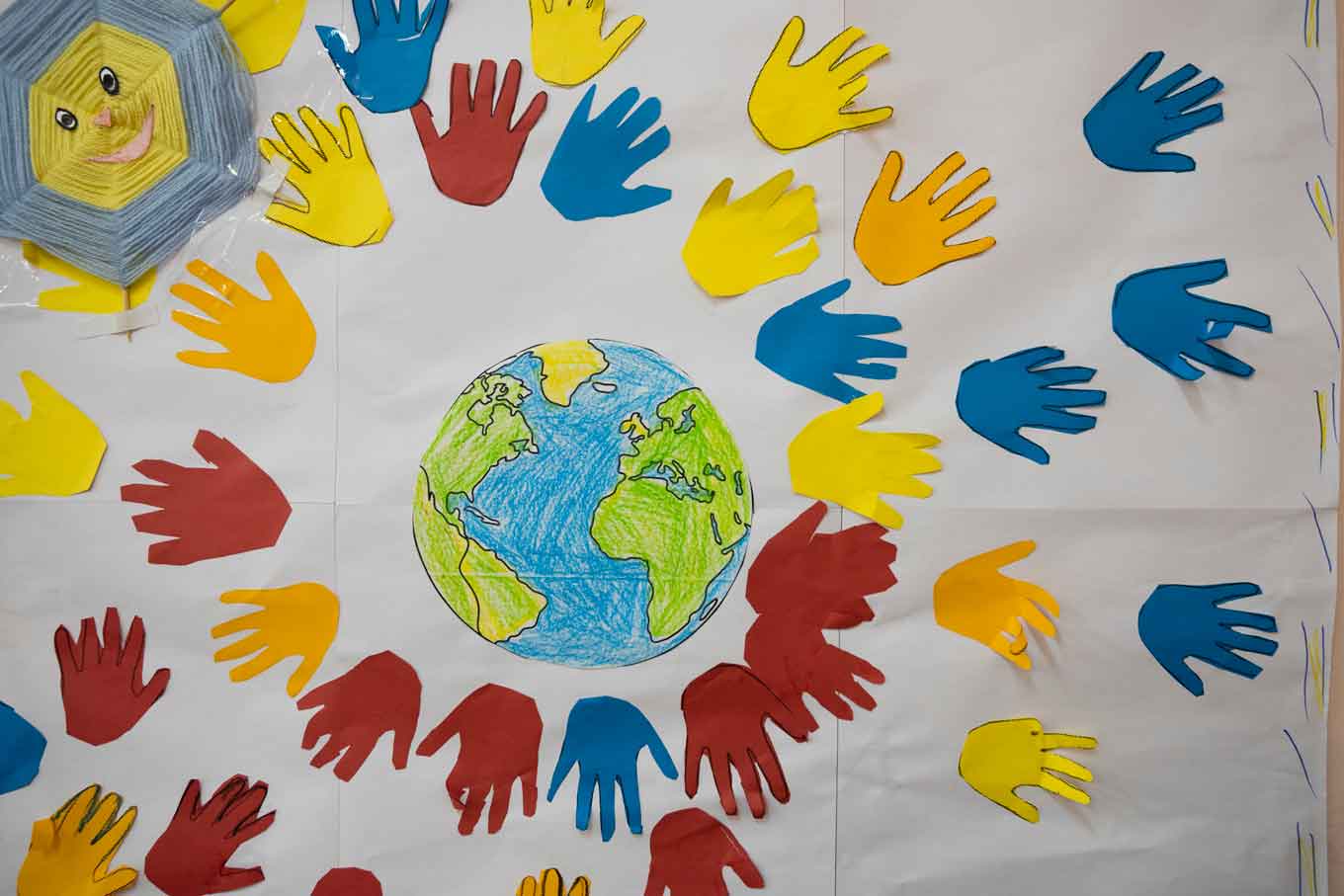 A children's art project includes a drawing of Earth and hands cut out of construction paper