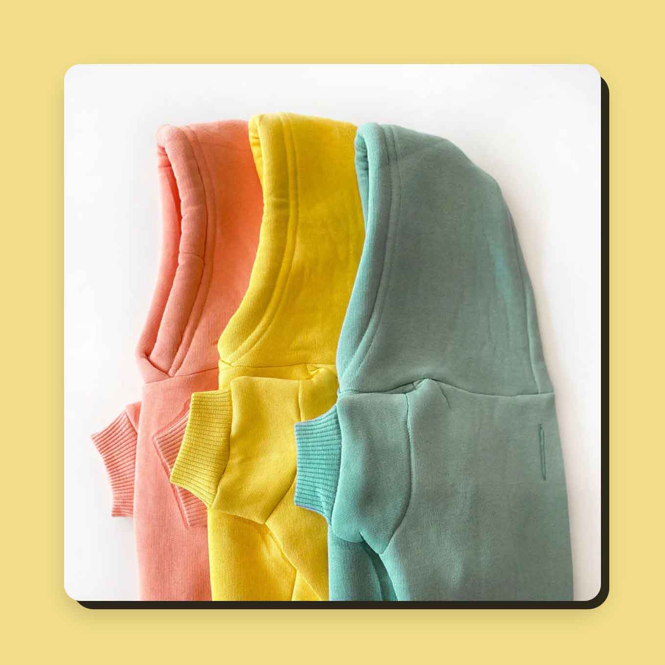 Three dog hoodies in peach, yellow, and mint