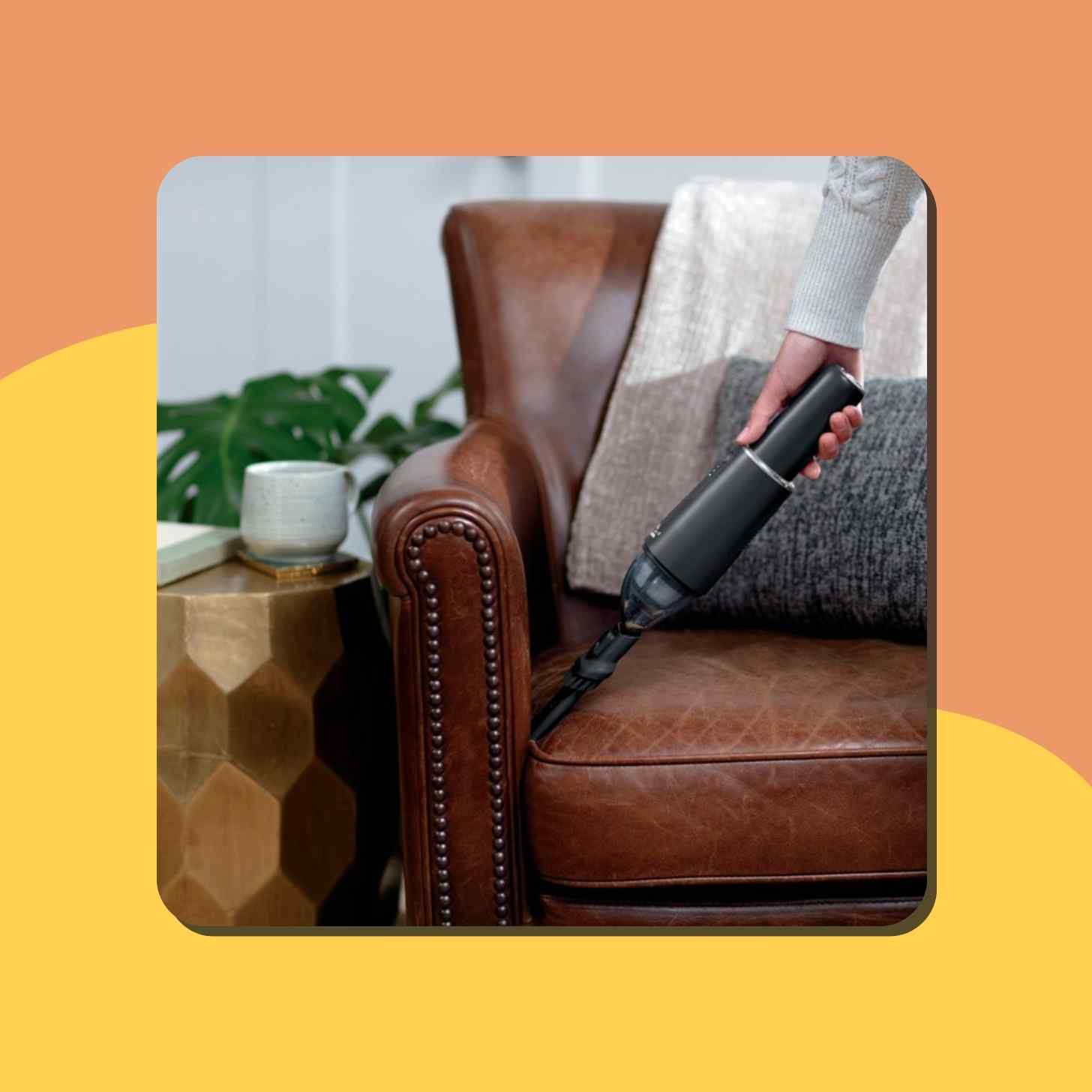 A Person Holding A Handheld Vacuum Cleaning A Sofa