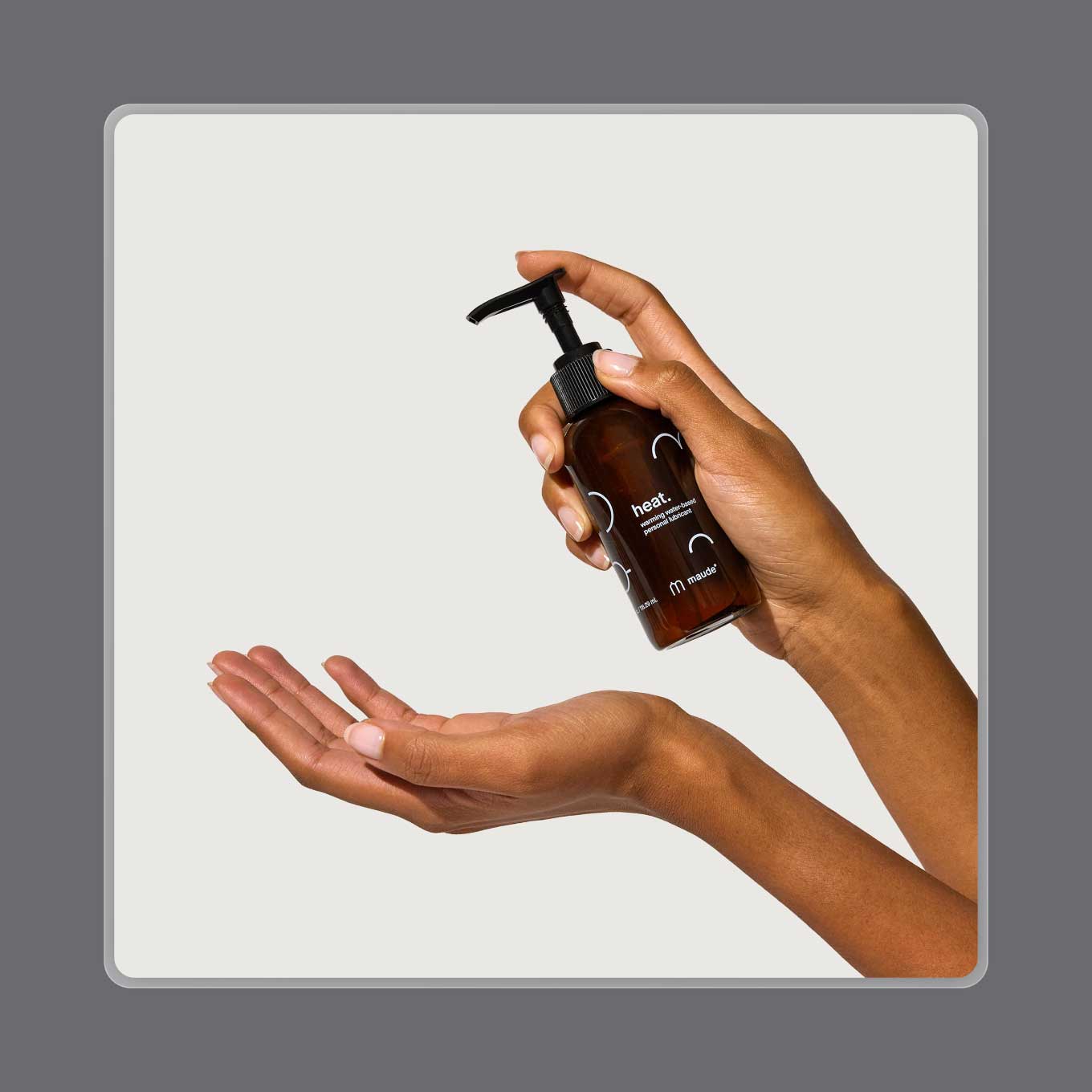 A hand holds up a bottle of Maude's heat lubricant