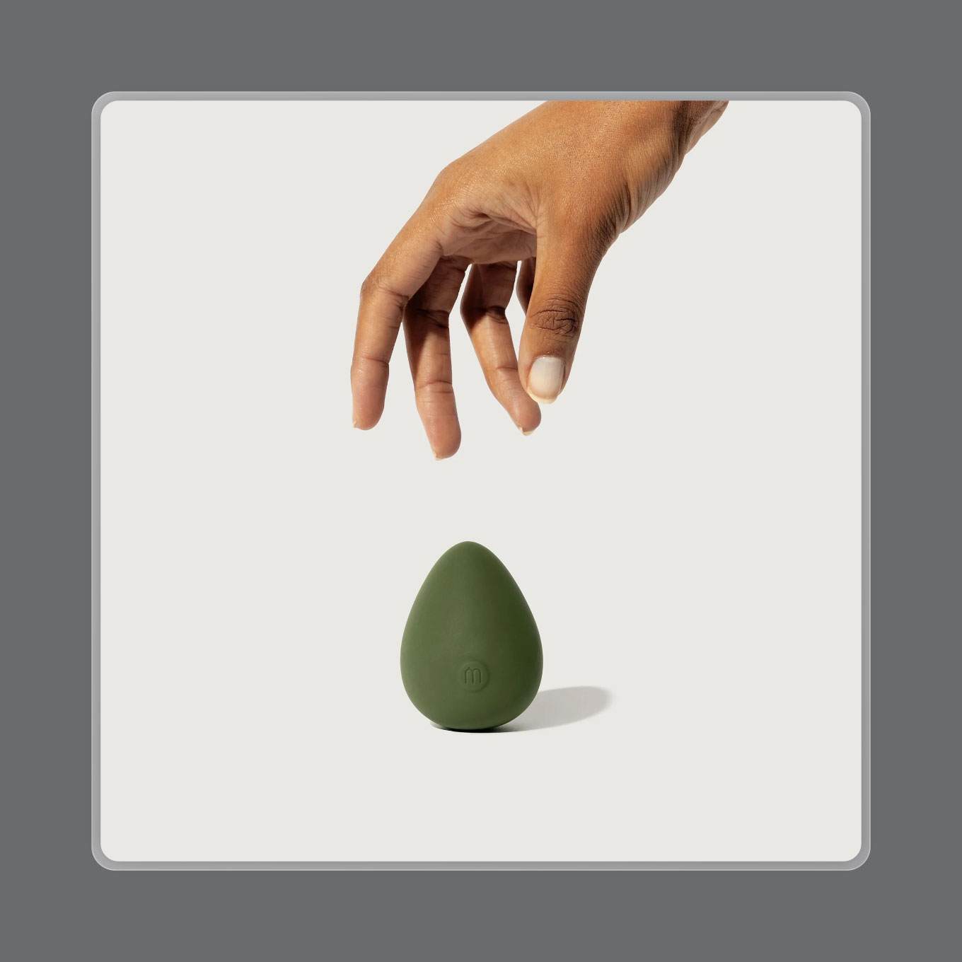 A hand reaches for a round, green sex toy
